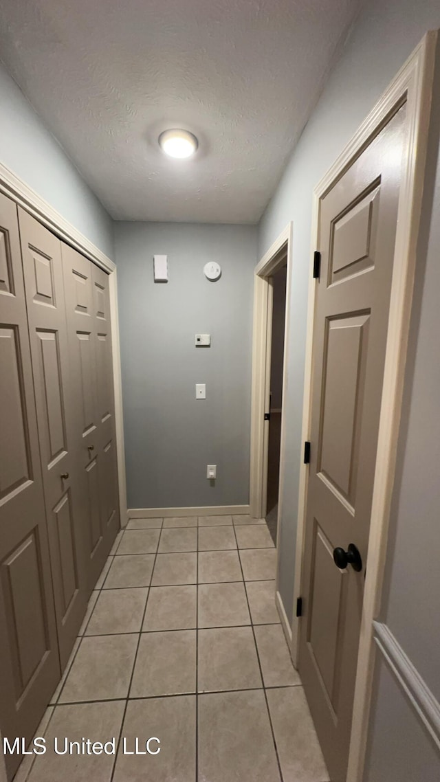 hallway featuring light tile patterned floors and a textured ceiling