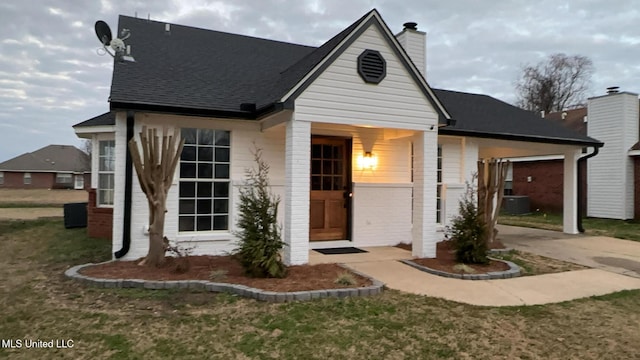 view of front facade featuring cooling unit, a front lawn, and a carport