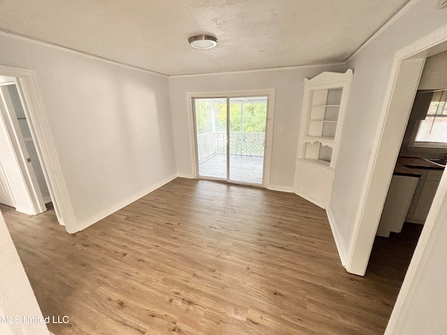 unfurnished room with crown molding, wood-type flooring, and a textured ceiling