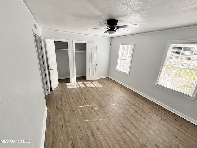 2123 Belvedere Dr, Jackson, MS 39204 - unfurnished bedroom with wood finished floors, two closets, baseboards, a textured ceiling, and a ceiling fan