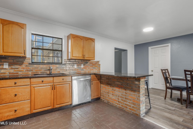 kitchen with dishwasher, a breakfast bar, sink, dark stone countertops, and kitchen peninsula