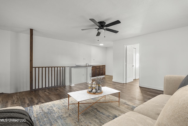 living room featuring ceiling fan, sink, and dark hardwood / wood-style floors