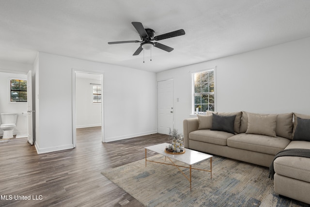 living room with ceiling fan and dark wood-type flooring