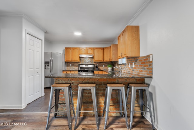 kitchen featuring kitchen peninsula, backsplash, stainless steel appliances, sink, and a breakfast bar area