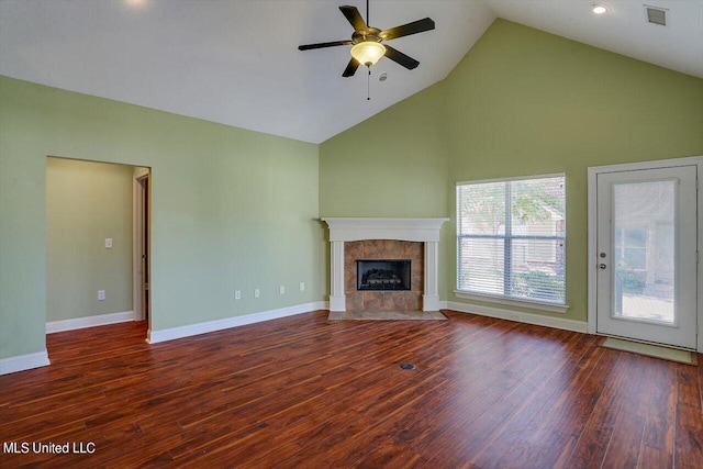 unfurnished living room with ceiling fan, a tiled fireplace, high vaulted ceiling, and dark hardwood / wood-style flooring