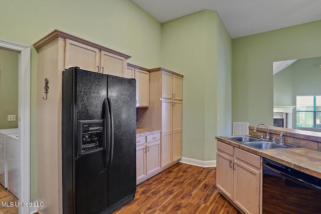 kitchen with washer and clothes dryer, sink, black appliances, light brown cabinetry, and dark hardwood / wood-style flooring