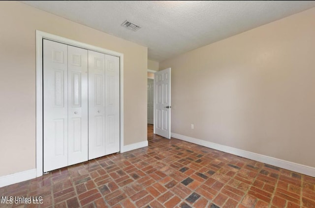 4127 Ceolia Taylor Rd, Moss Point, MS 39562 - unfurnished bedroom with brick floors, baseboards, a closet, and a textured ceiling