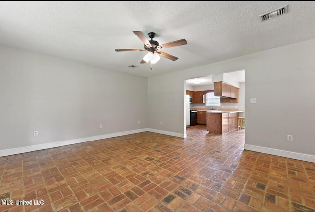 4127 Ceolia Taylor Rd, Moss Point, MS 39562 - unfurnished living room with a ceiling fan, baseboards, brick floors, a sink, and a textured ceiling