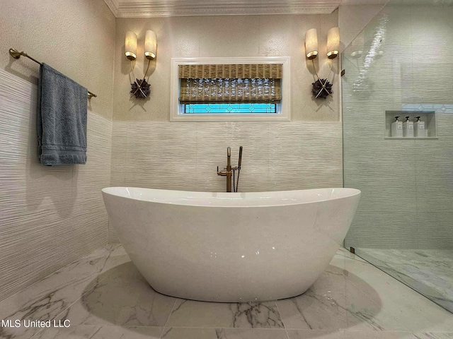 full bathroom featuring tile walls, marble finish floor, and a freestanding bath