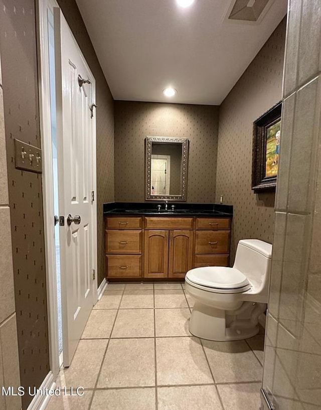bathroom with toilet, vanity, tile patterned floors, and wallpapered walls