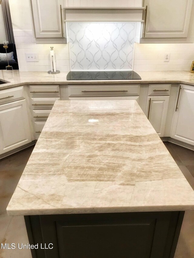 kitchen featuring backsplash, white cabinets, a kitchen island, and black electric cooktop