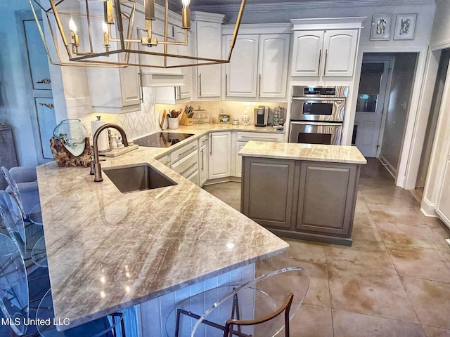 kitchen featuring a center island, light stone counters, a sink, stainless steel double oven, and black electric cooktop