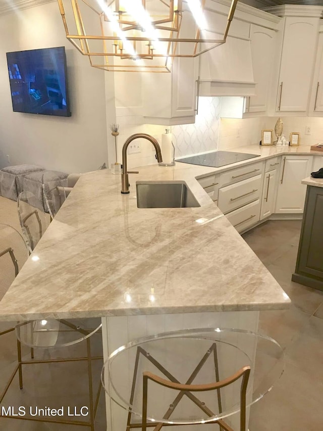 kitchen featuring black electric stovetop, a sink, and white cabinetry