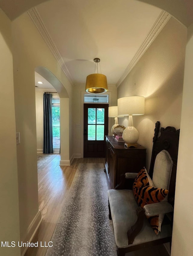 foyer with arched walkways, wood finished floors, a healthy amount of sunlight, and crown molding