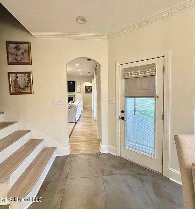 interior space with baseboards, arched walkways, stairs, and crown molding