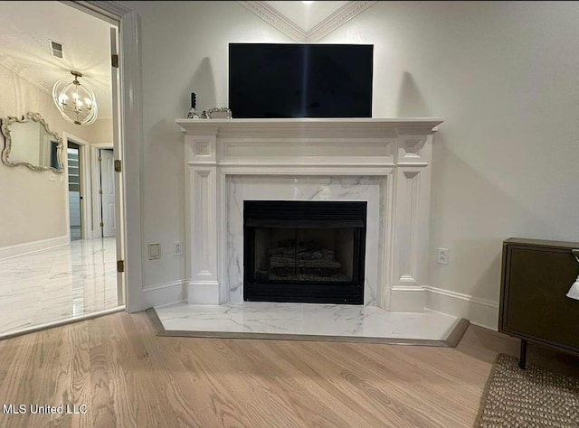 interior details with wood finished floors, a high end fireplace, a chandelier, baseboards, and visible vents