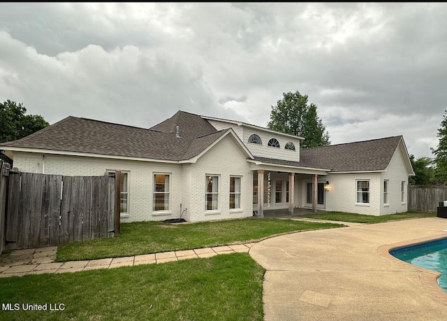back of property with a fenced in pool, fence, a patio area, a lawn, and brick siding