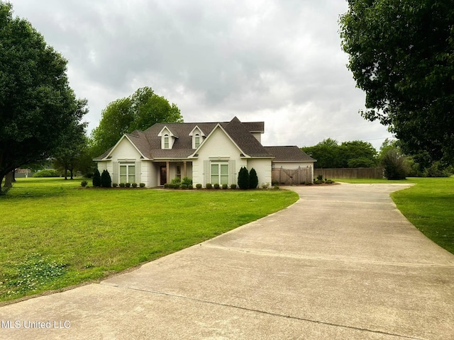 cape cod home with concrete driveway, a front lawn, and fence