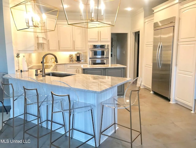 kitchen with light stone counters, stainless steel appliances, ornamental molding, a sink, and a peninsula
