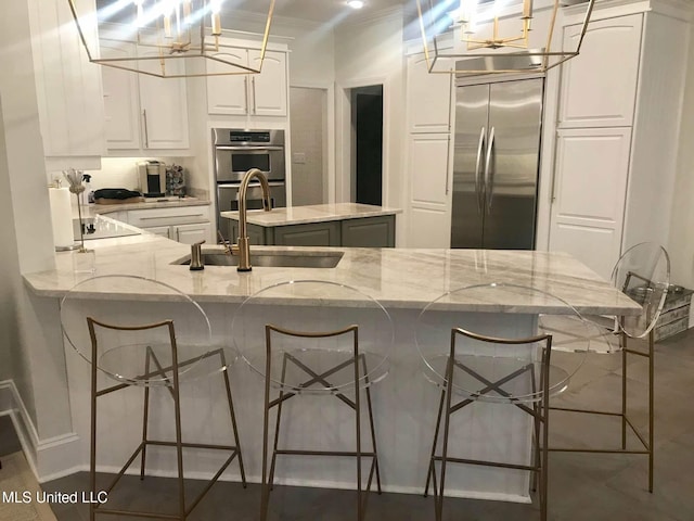 kitchen with stainless steel appliances, a kitchen breakfast bar, a peninsula, a sink, and white cabinetry
