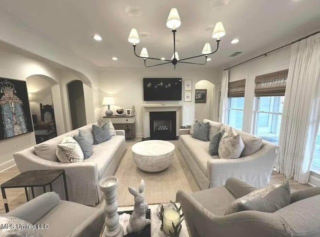 living area featuring arched walkways, visible vents, an inviting chandelier, baseboards, and recessed lighting