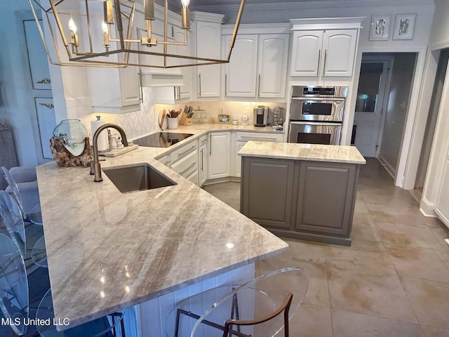 kitchen with stainless steel double oven, backsplash, a sink, light stone countertops, and black electric stovetop