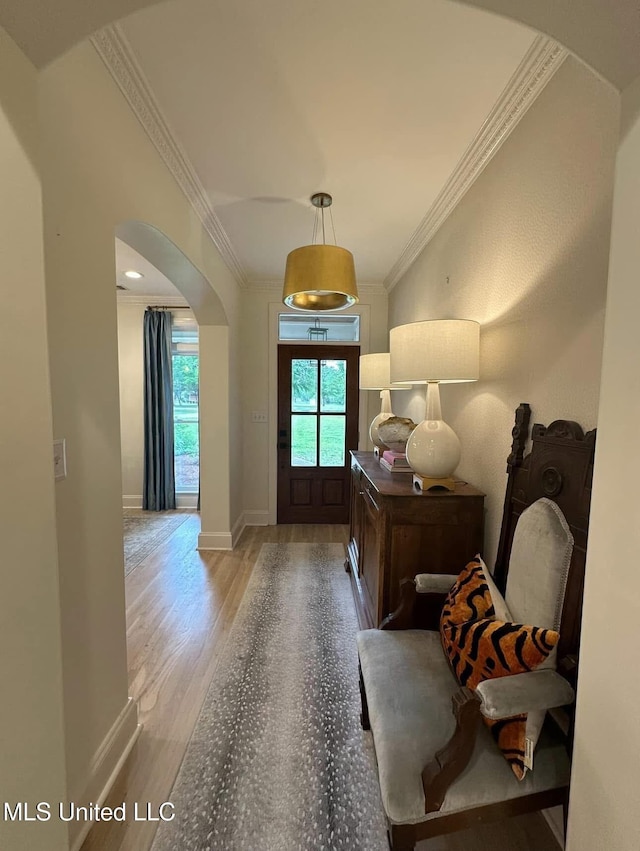 entryway featuring baseboards, wood finished floors, arched walkways, and crown molding