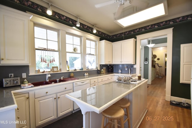 1211 River Rd, Greenwood, MS 38930 - kitchen featuring white dishwasher, white cabinetry, a kitchen island, and rail lighting