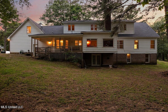 back house at dusk featuring a yard