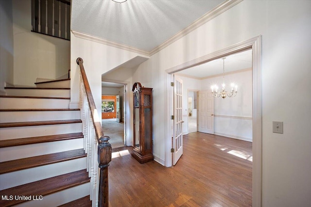 stairs featuring ornamental molding, hardwood / wood-style floors, a chandelier, and a textured ceiling