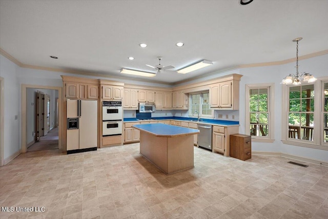 kitchen featuring sink, ceiling fan with notable chandelier, a kitchen island, stainless steel appliances, and ornamental molding