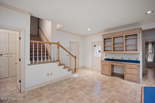 kitchen featuring crown molding, built in desk, and light brown cabinetry