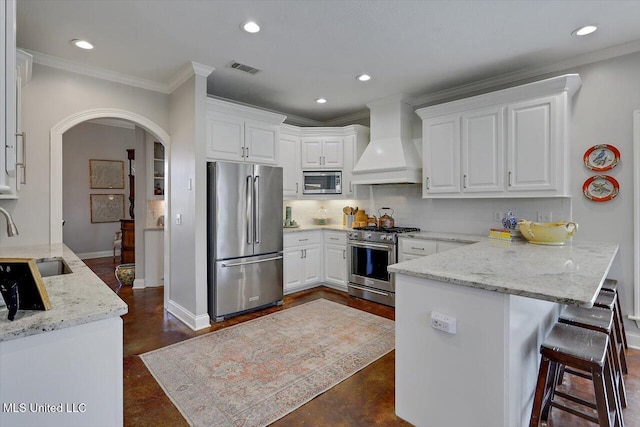 kitchen with white cabinetry, custom exhaust hood, stainless steel appliances, and arched walkways