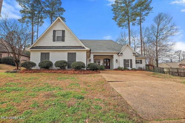 view of front of house featuring brick siding, fence, and a front lawn