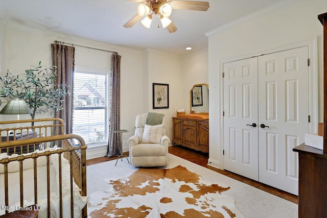 bedroom featuring baseboards, ceiling fan, wood finished floors, crown molding, and a closet