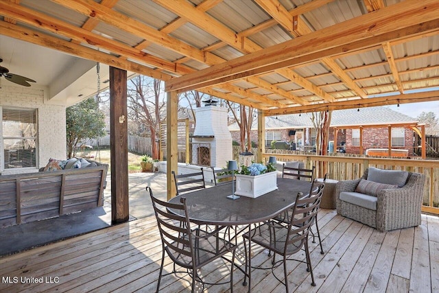 wooden deck with fence, an outdoor fireplace, outdoor dining area, and a ceiling fan