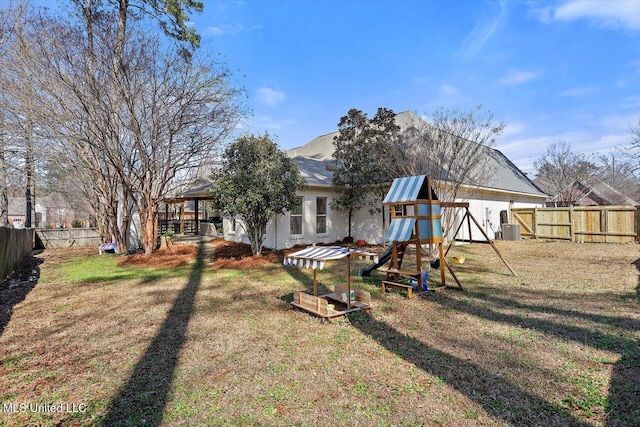 view of yard with central AC unit, a playground, and a fenced backyard