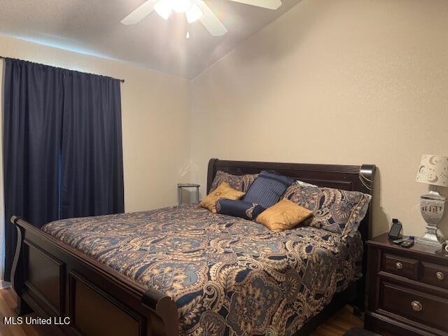 bedroom featuring dark wood finished floors, vaulted ceiling, and a ceiling fan
