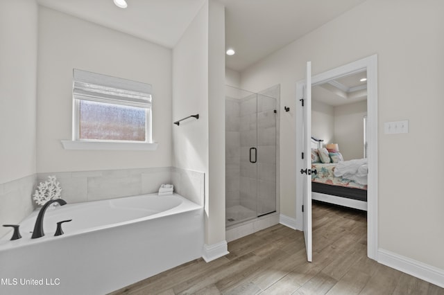 ensuite bathroom with baseboards, wood finished floors, ensuite bathroom, a garden tub, and a shower stall