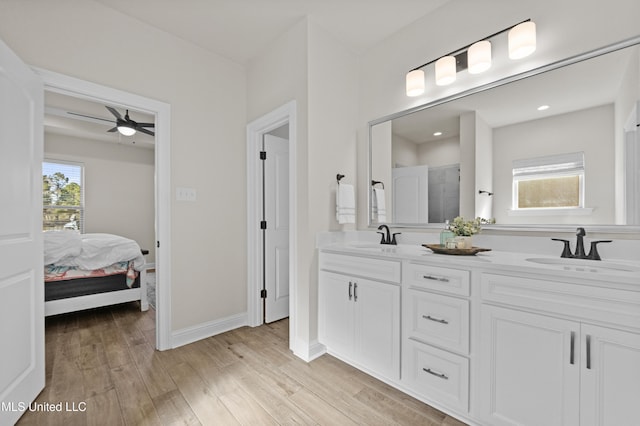 ensuite bathroom with a wealth of natural light, a sink, and wood finished floors