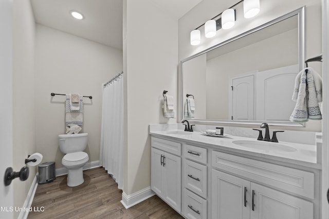 full bathroom with double vanity, wood finished floors, a sink, and toilet