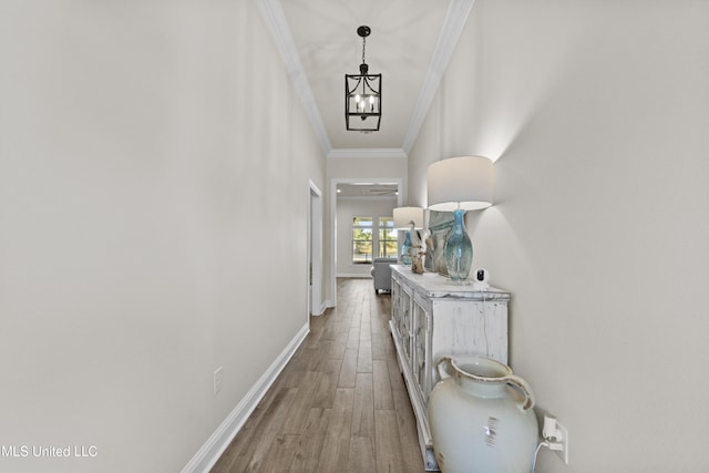 hall featuring baseboards, an inviting chandelier, wood finished floors, and crown molding