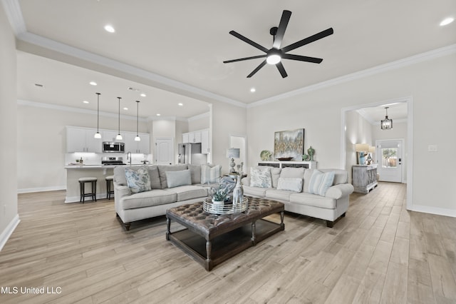 living area featuring baseboards, a ceiling fan, ornamental molding, light wood-style floors, and recessed lighting