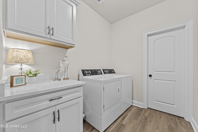 clothes washing area featuring light wood-type flooring, cabinet space, washing machine and dryer, and baseboards