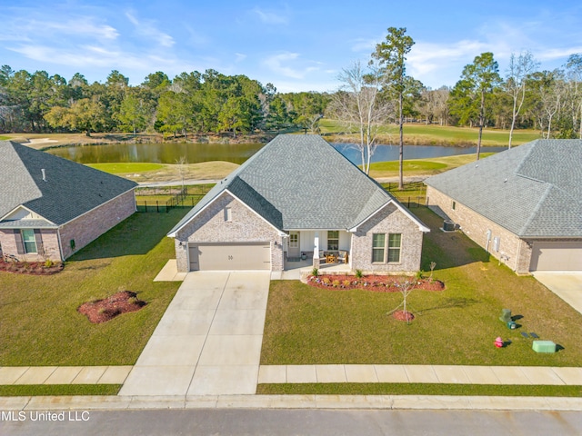 view of front of house with a garage, a water view, concrete driveway, roof with shingles, and a front yard