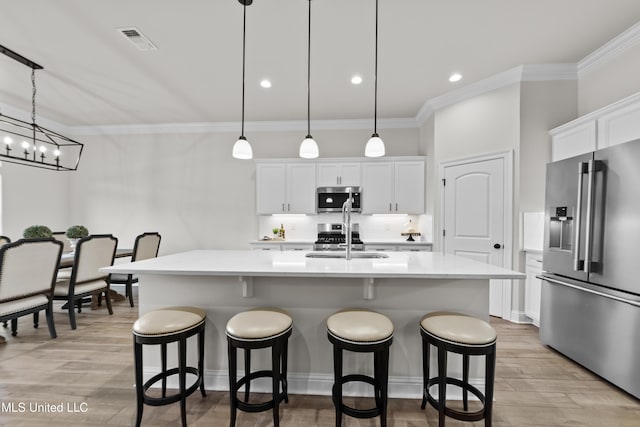 kitchen featuring visible vents, a kitchen island with sink, stainless steel appliances, light wood-style floors, and a sink