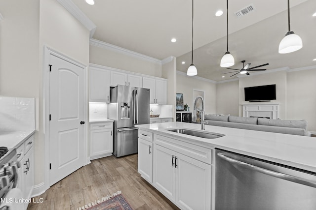 kitchen featuring a sink, white cabinets, light countertops, appliances with stainless steel finishes, and light wood-type flooring