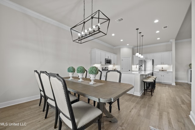 dining space featuring light wood-style floors, baseboards, visible vents, and ornamental molding