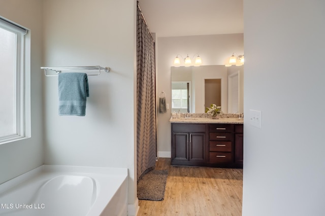15581 Ollie Ln, Biloxi, MS 39532 - bathroom featuring double vanity, a garden tub, and wood finished floors