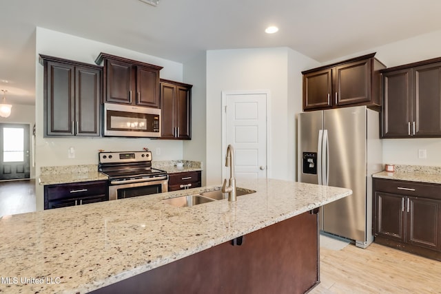 15581 Ollie Ln, Biloxi, MS 39532 - kitchen featuring stainless steel appliances, a sink, dark brown cabinets, light stone counters, and recessed lighting